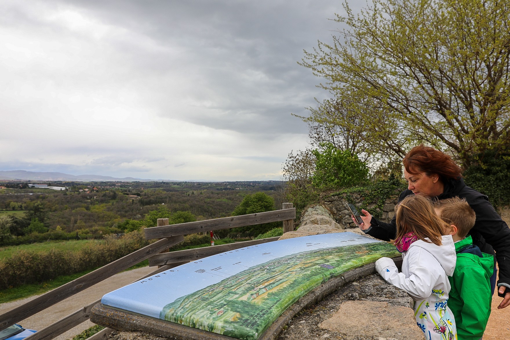 Une famille jouant aux Gnolus à Montagny. Ils sont en train de répondre à une énigme lancée par les Gnolus au niveau de la table d'orientation dans le Vieux Montagny.