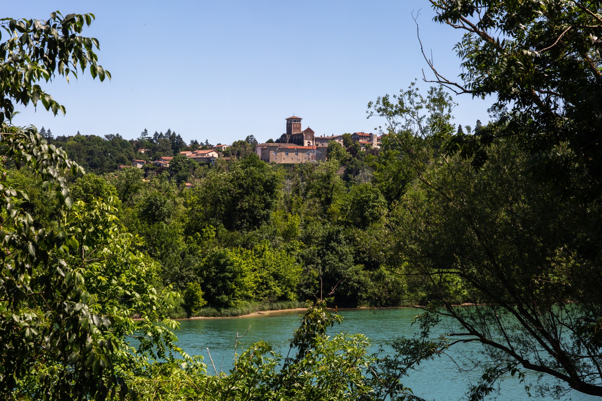 Vue sur le Rhône, avec au loin la colline et le château de la Porte à Ternay, avec des arbres encadrant la photo.