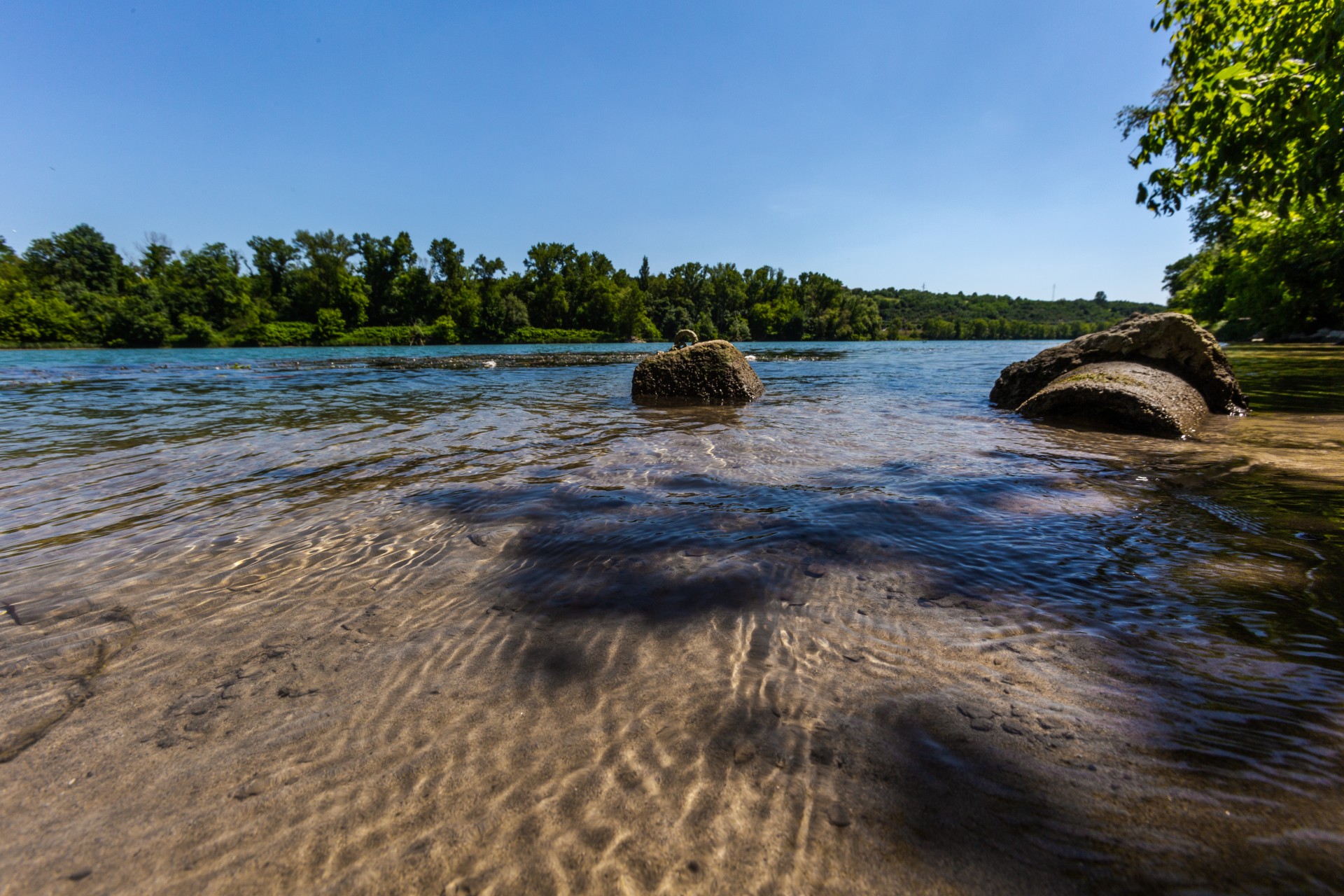 Vue sur le Rhône avec une eau translucide et des arbres verdoyants en arrière plan.