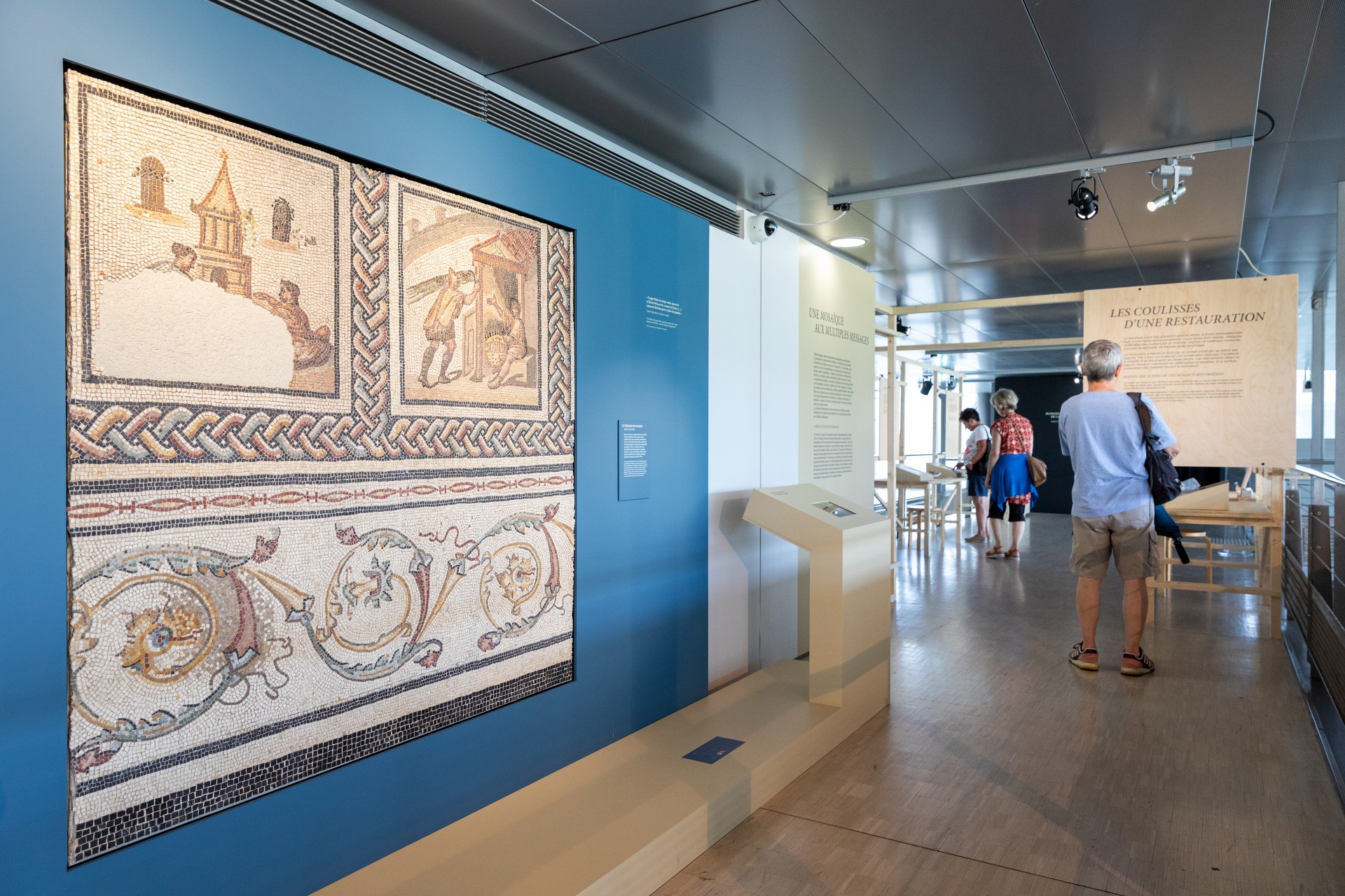 Pièce dans le musée de Saint-Romain en gal. On voit une mosaïque et des explications sur l'exposition. Un homme est en train de lire 